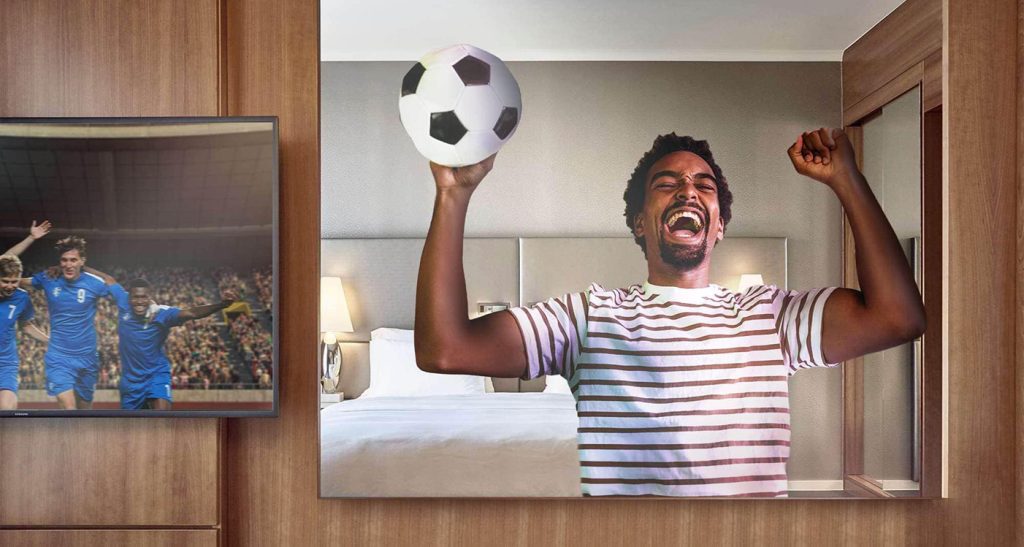 hotel room with smart tv connected to a football match and a client cheering to the screen