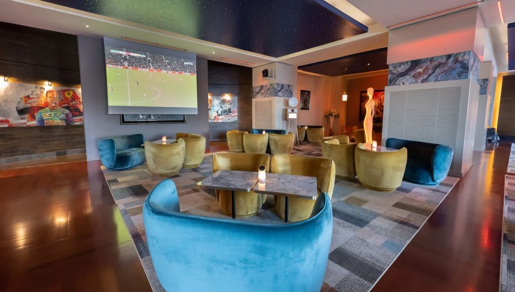 hotel’s communal lounge, equipped with large Smart TVs showing football matches